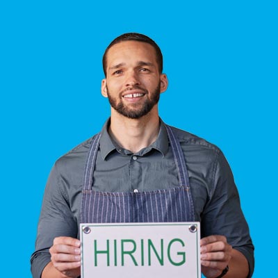 Man in apron holding HIRING sign